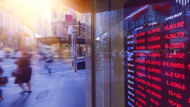 Une photo montrant l'écran d'un bureau de change à travers une vitrine au coin d'une rue.