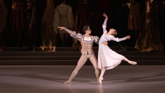 Un homme dansant le ballet tient dans son bras droit une ballerine effectuant une figure sur la pointe de son pied.