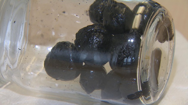 Une douzaine de billes noire dans un bocal de verre posé à l'horizontale Une douzaine de billes noire dans un bocal de verre posé à l'horizontale