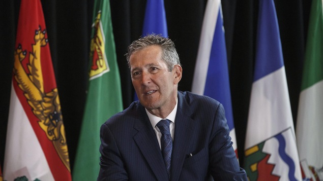 Le premier ministre du Manitoba, Brian Pallister, entouré de drapeaux. Le premier ministre du Manitoba, Brian Pallister, entouré de drapeaux.