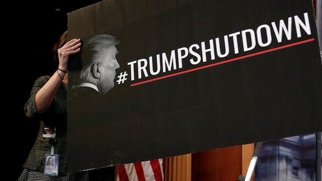 On peut lire sur la pancarte noire le mot-clic #TrumpShutDown