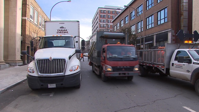 Deux camions de livraison circulent sur une rue à Montréal