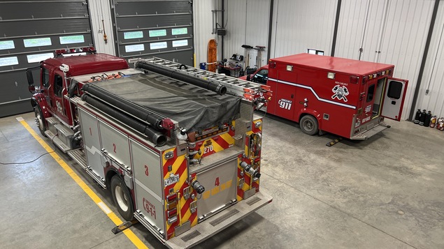 Un camion de pompier et un camion de service d'urgence dans le garage d'une caserne. 