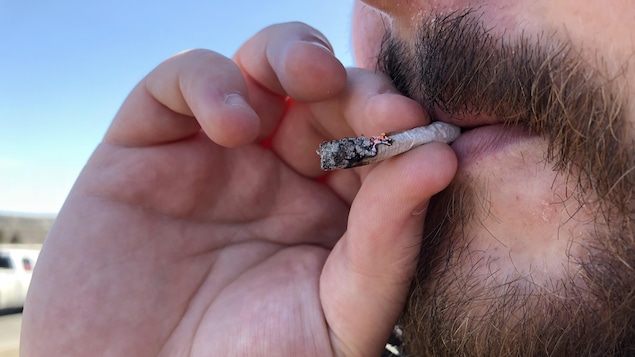Photo d'un homme à barbe qui fume un joint.