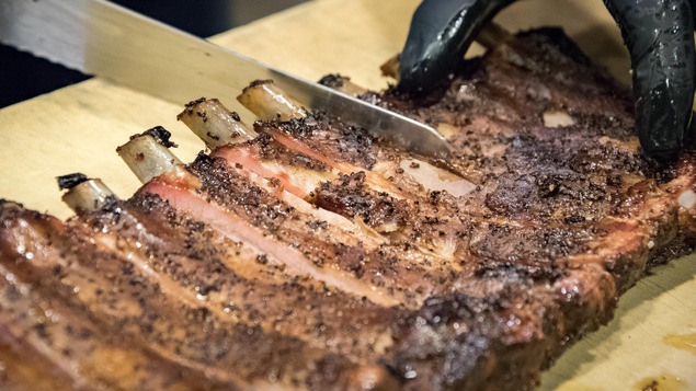 Des côtes de porc fumées sont tranchées au couteau Des côtes de porc fumées sont tranchées au couteau