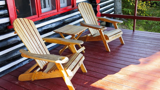 Deux chaises adirondack sur la terrasse d'un chalet en bois