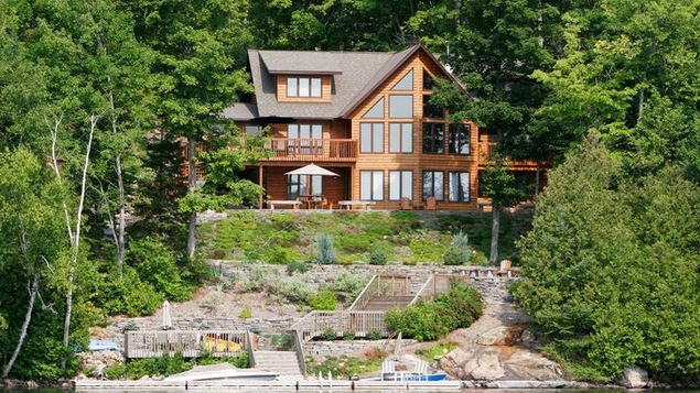 Un chalet en bordure d'un lac. Des escaliers descendent jusqu'au lac parmi des rochers.
