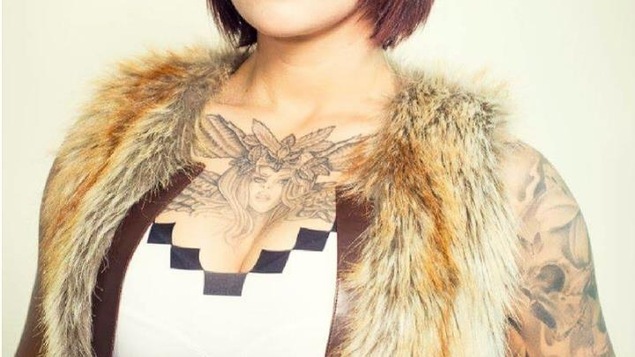 Une femme vêtue légèrement arbore plusieurs tatouages