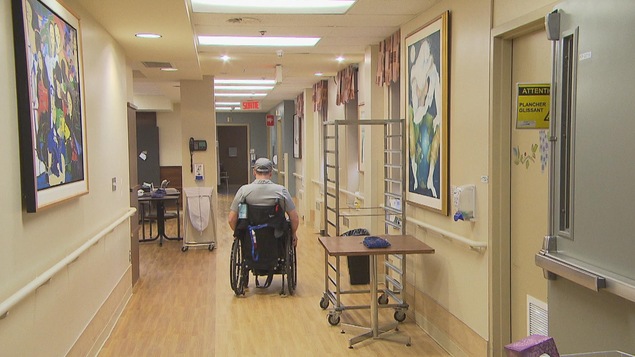 Une personne se déplace en fauteuil roulant dans un corridor du centre d'hébergement