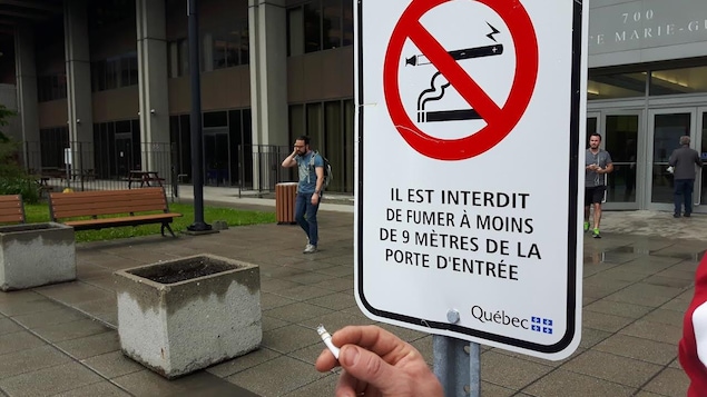 Une affiche qui signale l'interdiction de fumer à moins de 9 mètres d'une porte Une affiche qui signale l'interdiction de fumer à moins de 9 mètres d'une porte