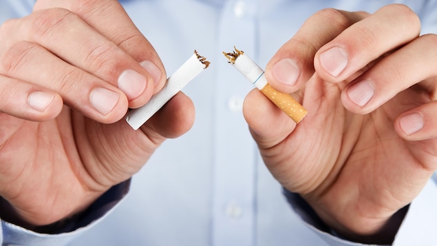 Un homme brise une cigarette en deux
