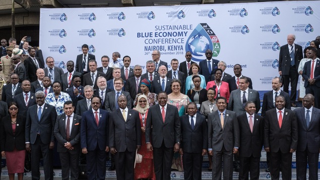 Des chef d'état et des ministres posent pour une photo de groupe devant une banderole de la conférence sur l'économie bleue durable.