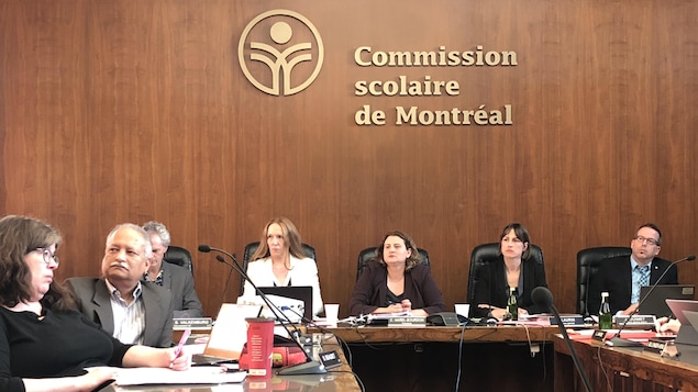 Des hommes et des femmes assis dans une salle de conseil.