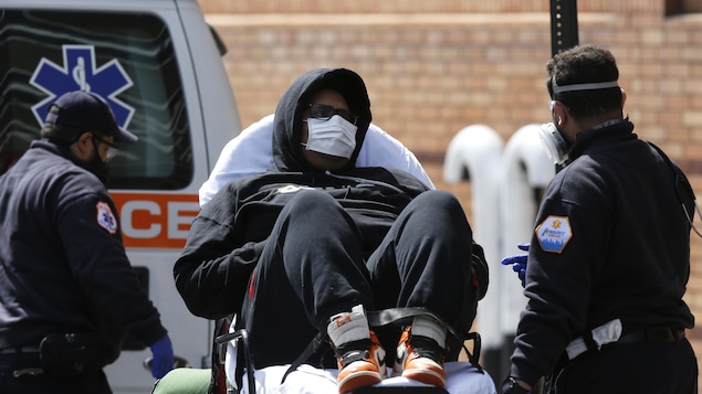 Un homme allongé sur une civière porte un masque de protection médical.