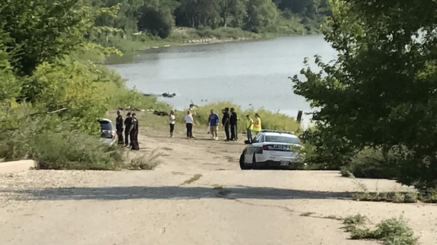 Des agents et des voitures de police près d'un cours d'eau