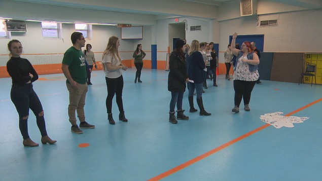Des personnes en ligne dans un gymnase s'apprêtent à jouer à la course privilège.