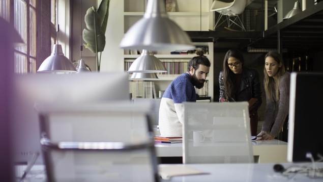 Trois personnes travaillent ensemble dans un espace collaboratif.