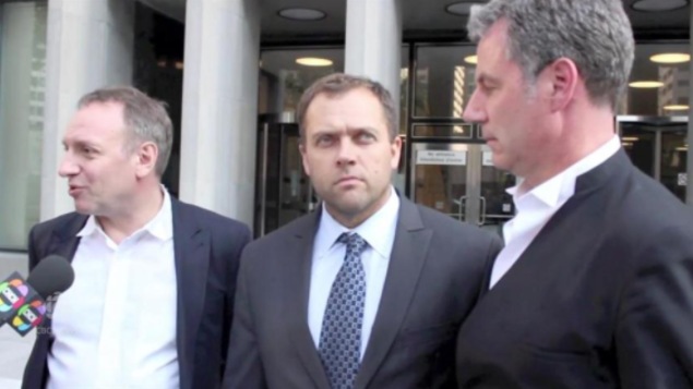 Une photo de trois hommes sortant d'un tribunal