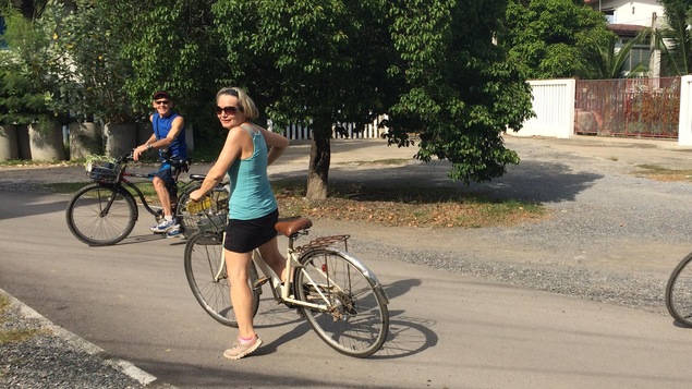 Une femme et un homme sont sur leur vélo et regardent la caméra.