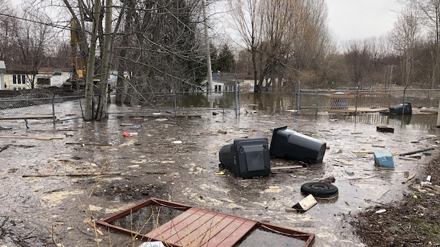 De nombreux débris jonchent une rue dans laquielle il reste un peu d'eau.