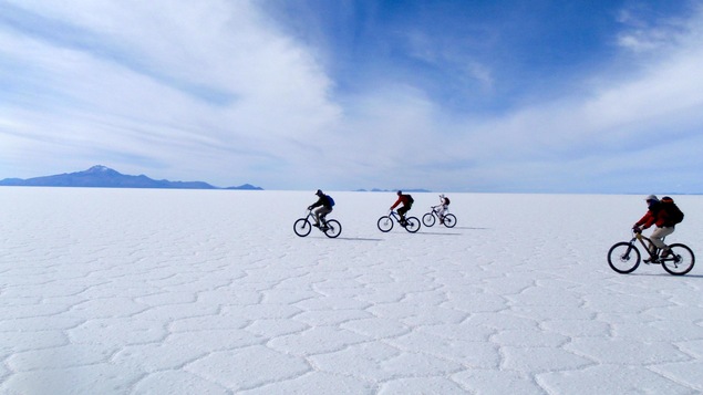 Des cyclistes roulent sur une surface couverte de sel s'étendant à perte de vue.