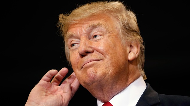 Le président des États-Unis Donald Trump porte la main à son oreille pour écouter les cris de la foule, le 23 août 2017.
