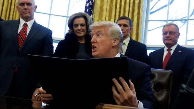 Le président américain Donald Trump, la bouche ouverte, venant de signer un décret dans le bureau ovale de la Maison-Blanche.