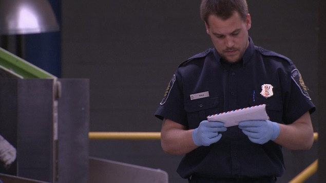 Un agent des services douaniers examine une lettre. Un agent des services douaniers examine une lettre.