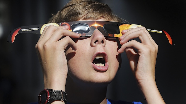 Un jeune garçon essaie des lunettes en vue de l'éclipse solaire de lundi.