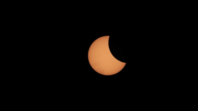 Croissant de lune passant devant le soleil