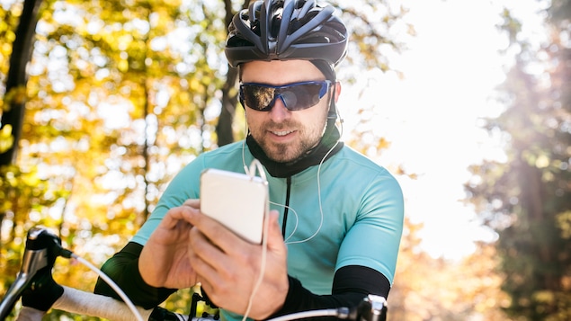 Un cycliste utilise son téléphone portable alors qu'il se trouve sur sa bicyclette. Il porte également des écouteurs.