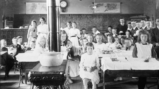 Des enfants sont assis dans une salle de classe pendant l'heure du dîner.