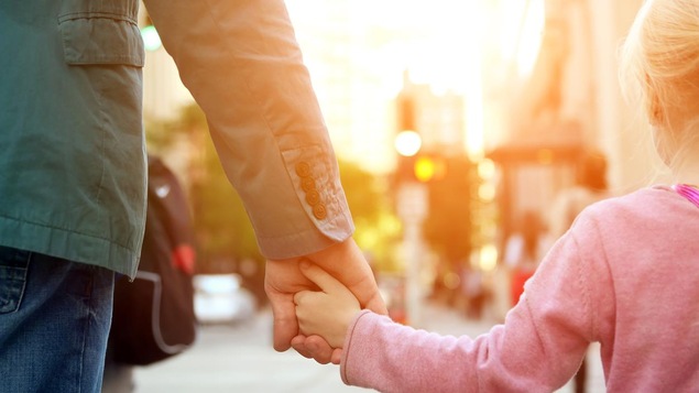 Un père et sa fille se promènent dans la rue.