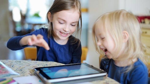 Deux fillettes rient et jouent avec une tablette