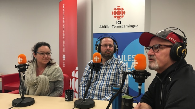 Trois personnes sont assises devant un micro autour d'une table.