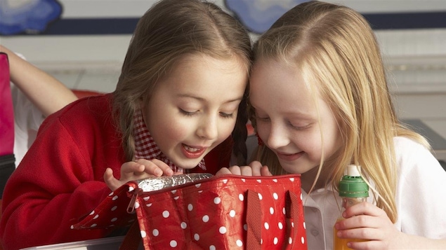 Des enfants regardent l'intérieur d'une boîte à lunch.