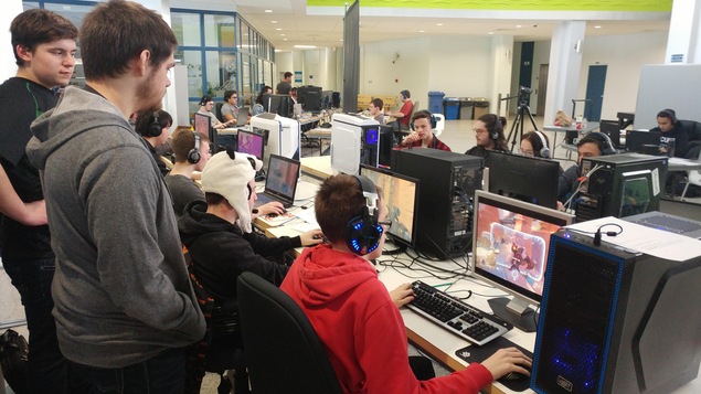 Un entraîneur derrière des joueurs de sport électronique de l'équipe Les Capitaines du Cegep de Matane jouant sur leur ordinateur dans une salle de l'école. Un entraîneur derrière des joueurs de sport électronique de l'équipe Les Capitaines du Cegep de Matane jouant sur leur ordinateur dans une salle de l'école.