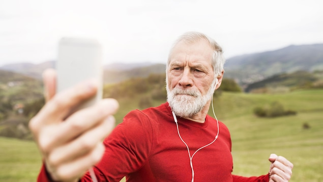 Un homme d'un certain âge prend un selfie en s'entraînant à l'extérieur.