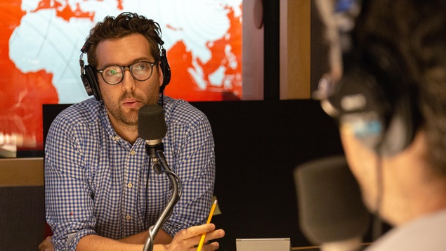 Une photo montrant Fabien Loszach, qui porte des lunettes rondes et une chemise à petits carreaux bleus.