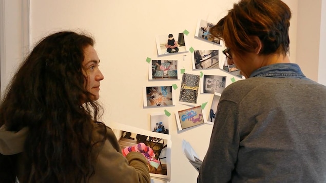 Deux femmes discutent et regardent les photos collées au mur. Deux femmes discutent et regardent les photos collées au mur.