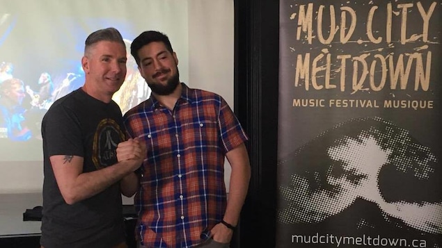 Les deux hommes se serrent la main devant l'affiche du festival. Les deux hommes se serrent la main devant l'affiche du festival.