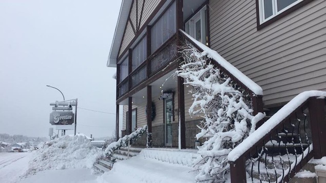 Un bâtiment avec une affiche de Fourrures Grenier, en hiver.