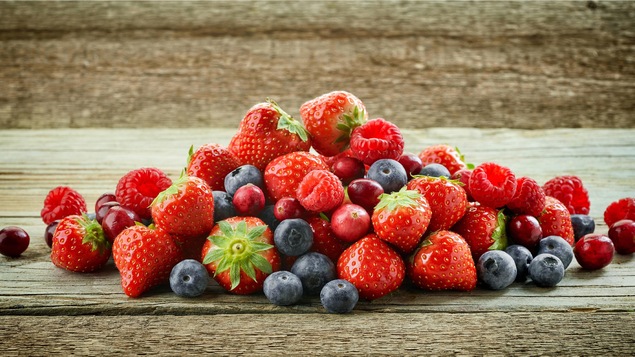 Une table où reposent Framboises, bleuets et petits fruits