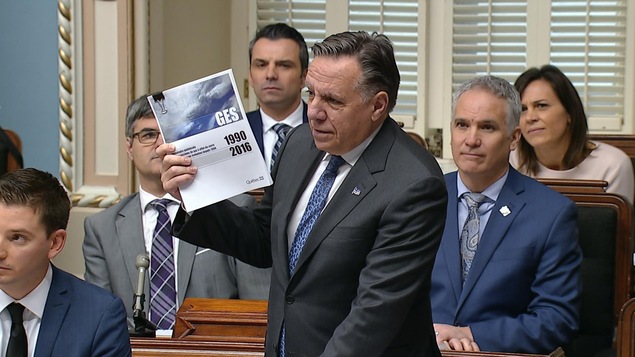 François Legault tient dans ses mains le plus récent bilan des émissions de GES du ministère de l'Environnement.