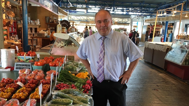 Monsieur Marchand debout près d'un étalage de légumes au Marché du Vieux-Port Monsieur Marchand debout près d'un étalage de légumes au Marché du Vieux-Port