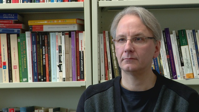 Frédéric Boily dans son bureau, devant une bibliothèque bien garnie en ouvrages.
