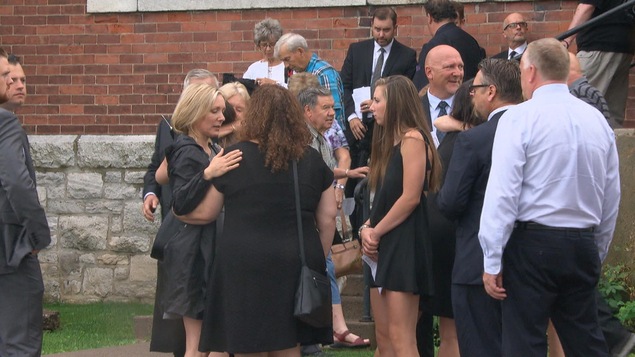 Des proches se recueillent devant une église.