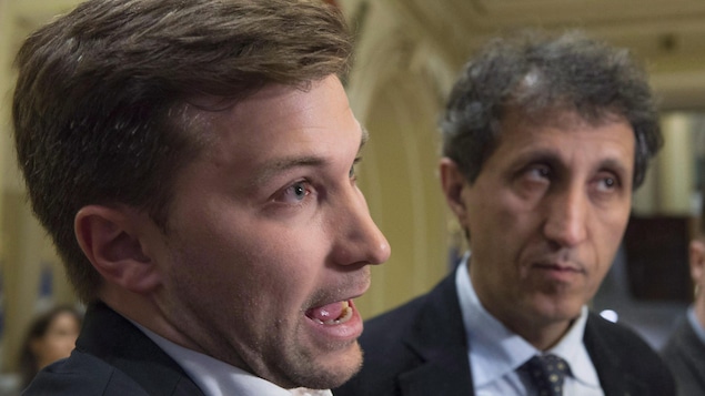 Deux hommes regardant des journalistes devant eux. Le plus jeune répond à une question et est en avant-plan. Deux hommes regardant des journalistes devant eux. Le plus jeune répond à une question et est en avant-plan.