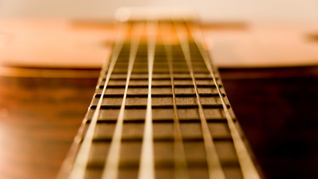 Les cordes d'une guitare acoustique vibrent.