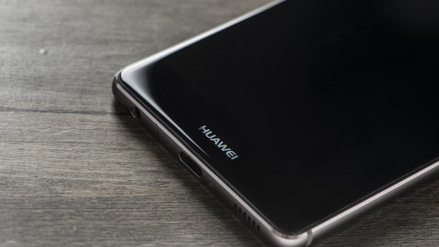 Un téléphone intelligent de la marque Huawei est posé sur une table en bois.